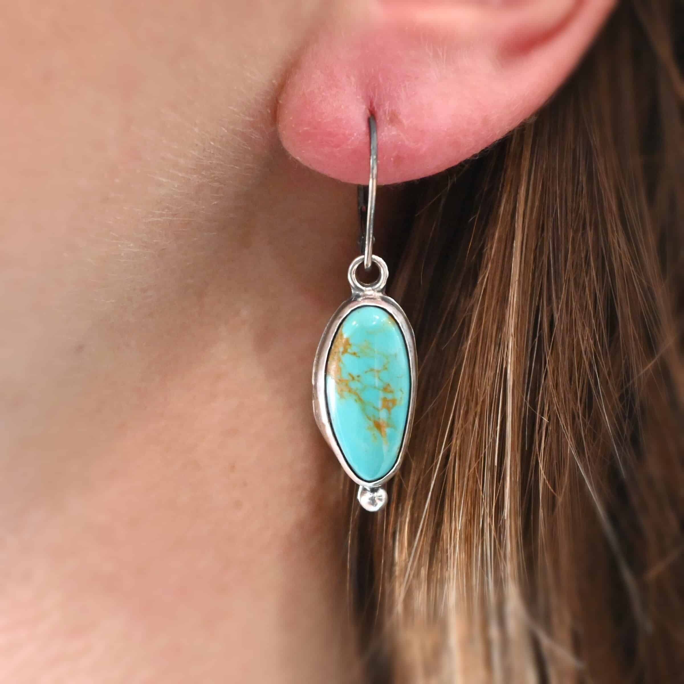 "Vivi" Earrings. Sterling Silver & Turquoise. Left earring has a circular turquoise and right earring is an oval. Each one has a ball of silver beneath it and silver ear wires.